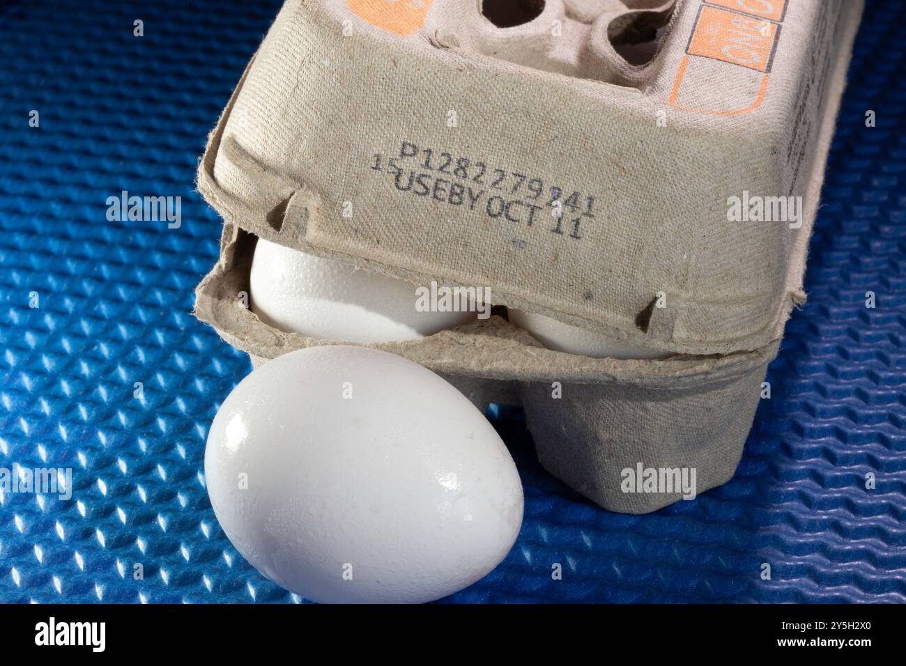 Closeup of an egg carton and whole white egg with an expiration date
