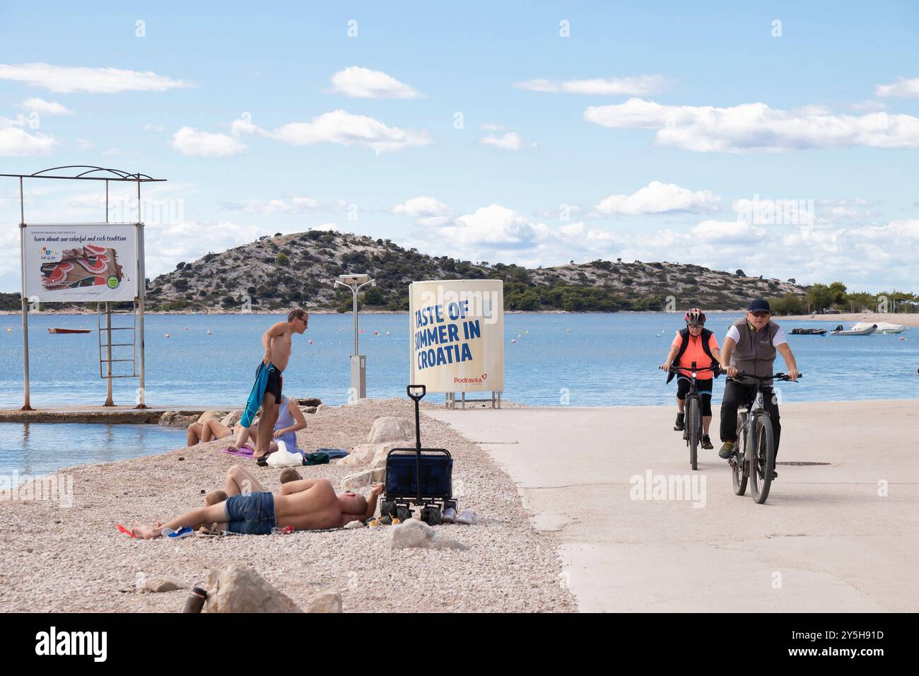 Vodice, Croatia - September 14, 2024: People swimming and riding bikes on the beach in off season Stock Photo