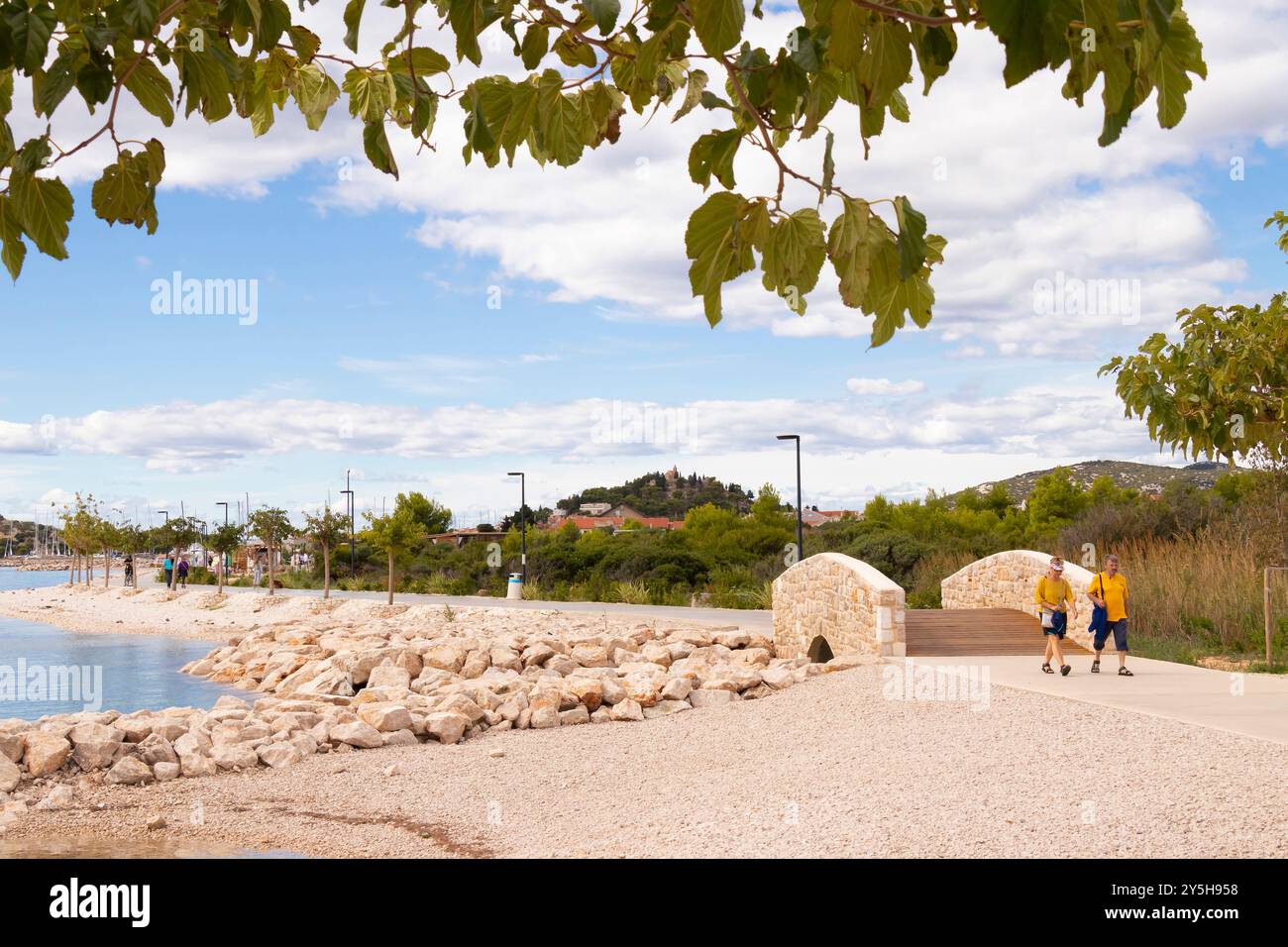 Tribunj, Croatia - September 14, 2024: Beach and promenade by the sea with few people walking Stock Photo