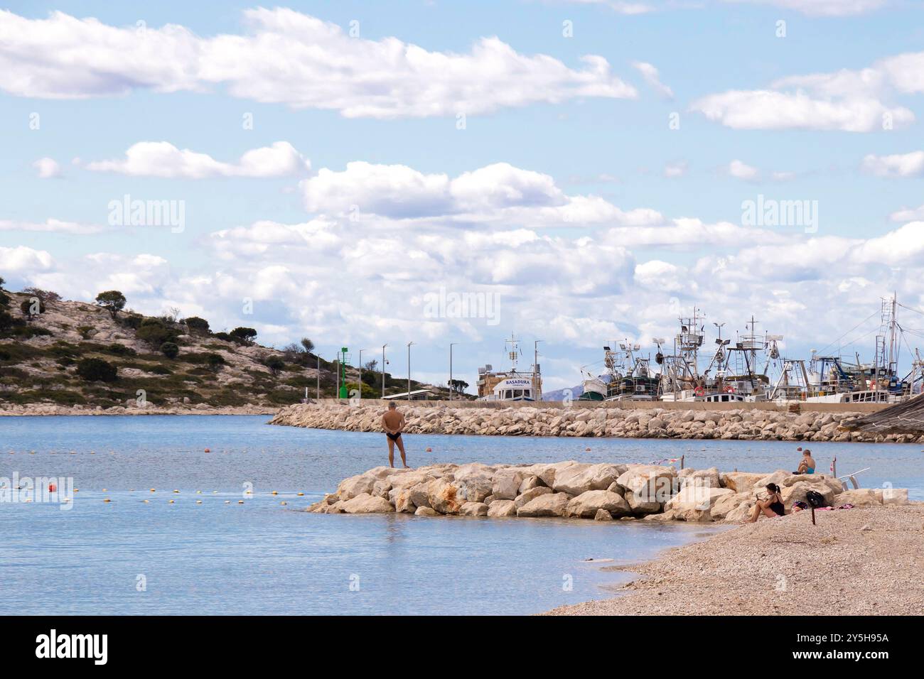 Tribunj, Croatia - September 14, 2024: Beach in off season with few people and fishing boats in the background Stock Photo