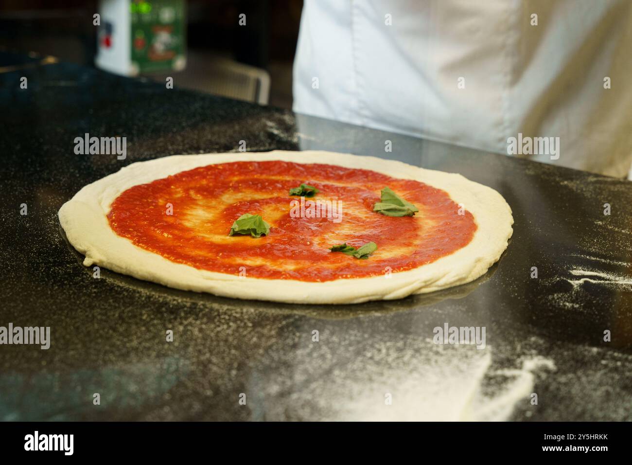 A chef preparing a pizza with tomato sauce Stock Photo