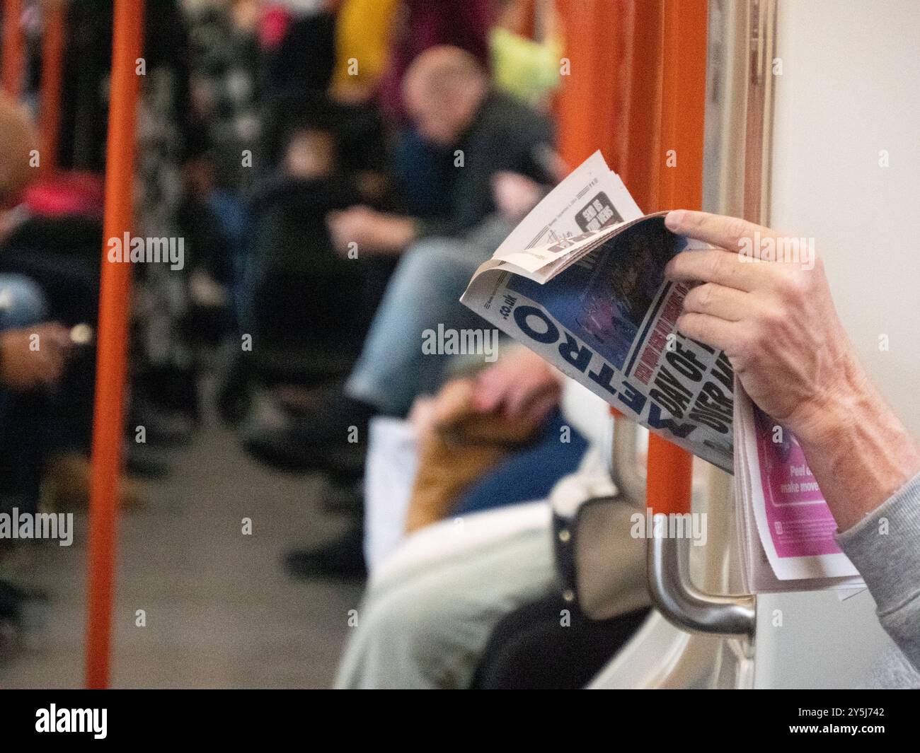 Man reading free Metro newspaper on overground train in Central London Stock Photo