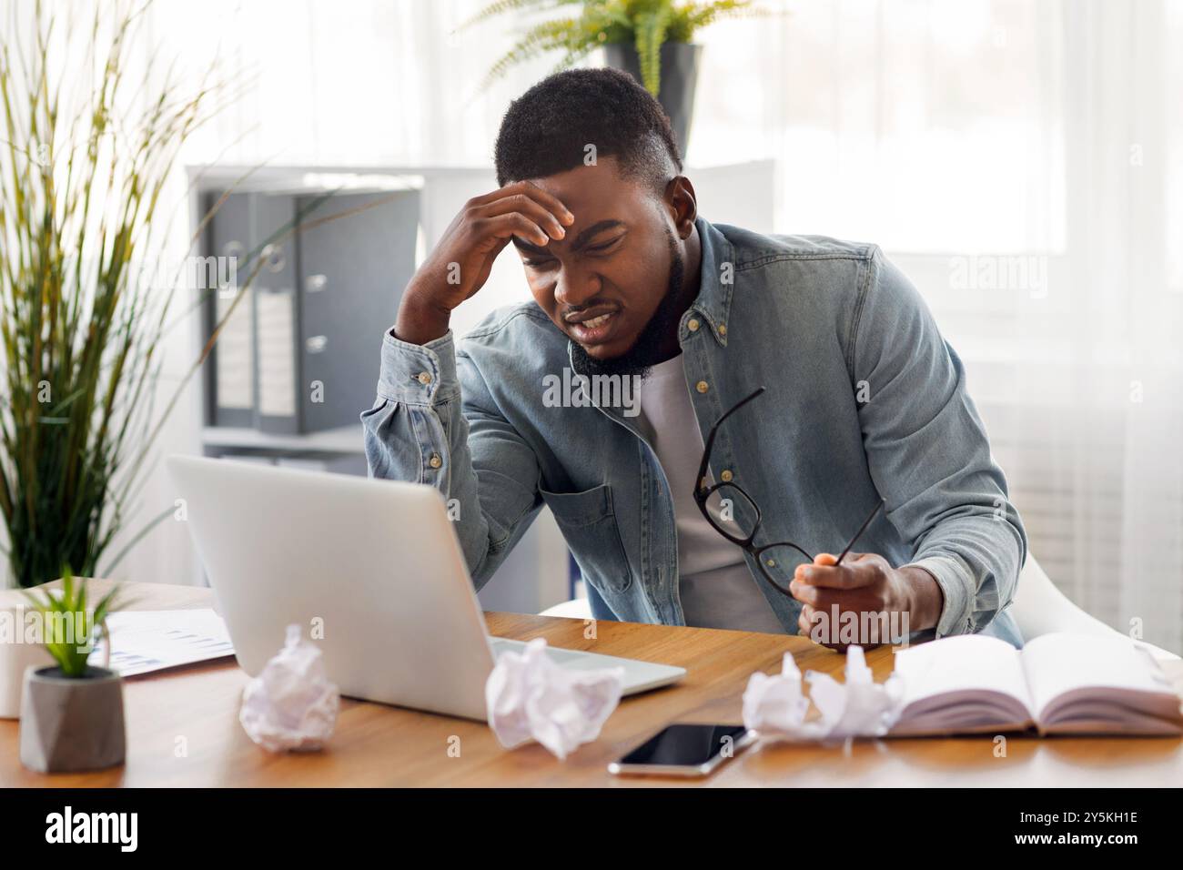 Annoyed black employee looking at laptop screen with despair Stock Photo