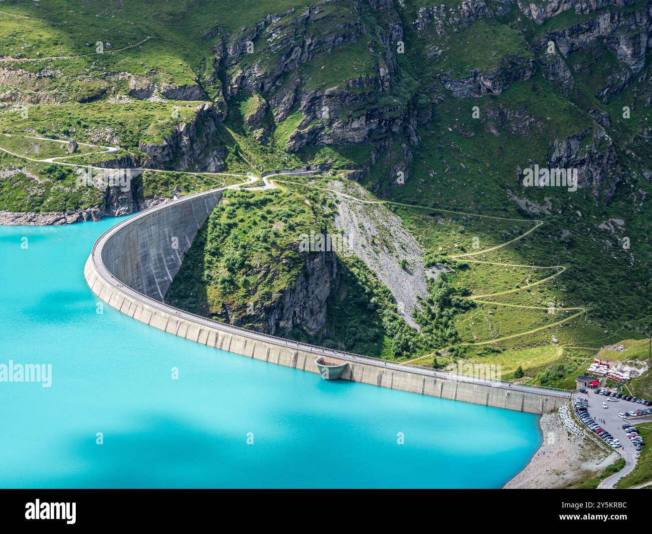 Dam of the Moiry lake,  Lac de Moiry, turquoise glacial water,  parking lot and restaurant at the dam, Valais, Switzerland Stock Photo