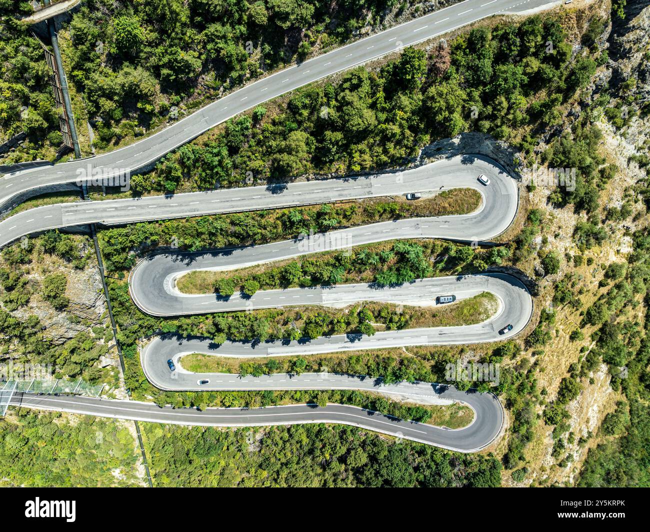 Mountain pass road with multiple hairpins, water pipeline, aerial view, drone shot.  Valais, Switzerland Stock Photo