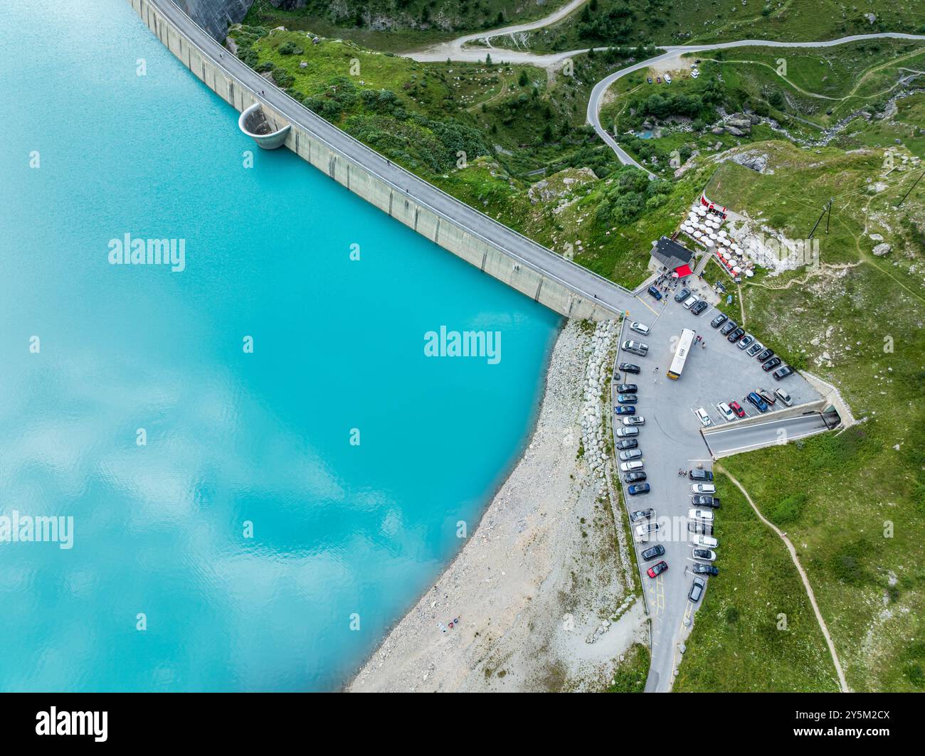 Dam of the Moiry lake,  Lac de Moiry, turquoise glacial water,  parking lot and restaurant at the dam, aerial view, Valais, Switzerland Stock Photo