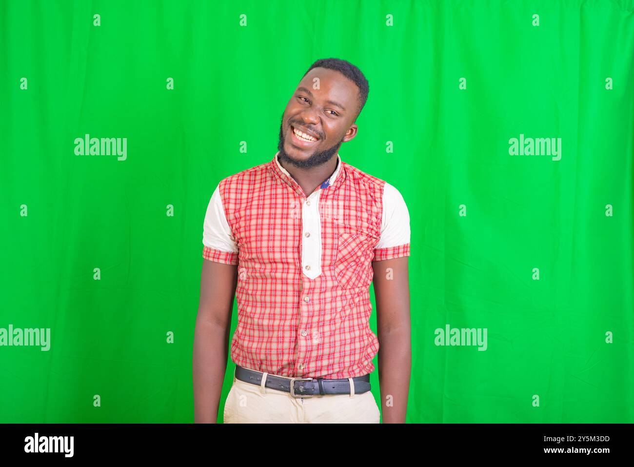 portrait of a handsome young man standing against green background ...