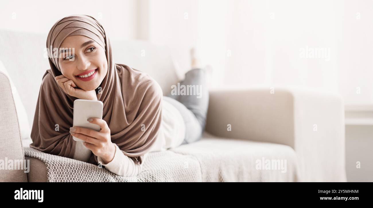 Romantic arab girl in hijab relaxing on sofa with smartphone Stock ...