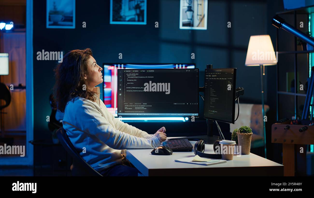 IT specialist working from home, testing and deploying programs using augmented reality. Programmer checking code on computer monitor and AR visualization, sitting at desk chair in apartment, camera A Stock Photo