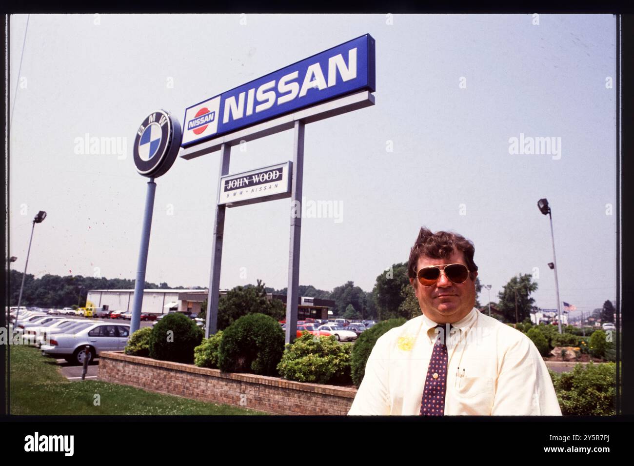 A salesman stands proudly in front of John Wood BMW-Nissan dealership ...