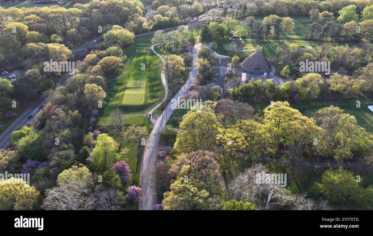 Aerial view of a lush green park with winding paths and a unique dome ...