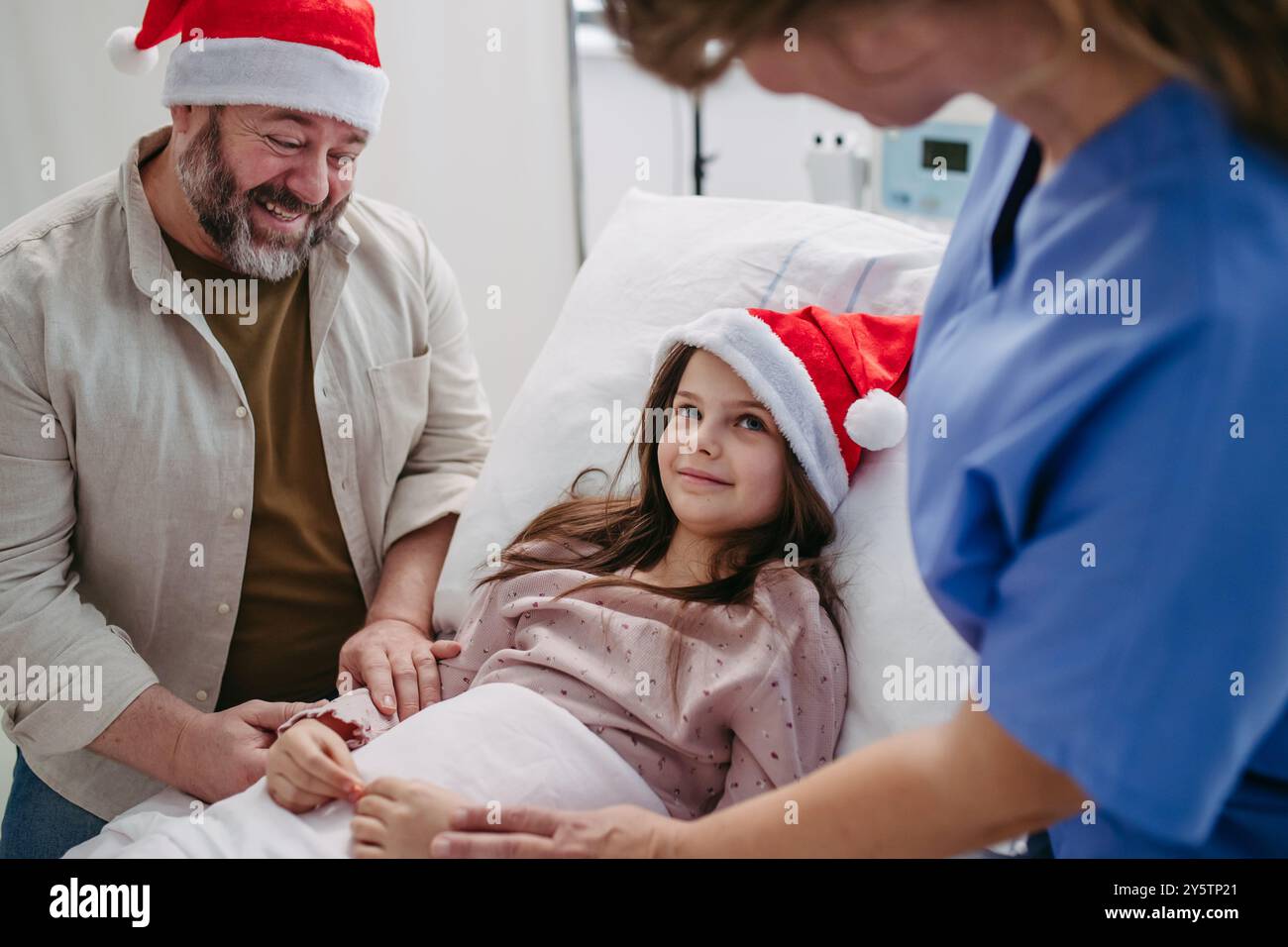 Father beside daughter on hospital bed. Sick little girl spending ...