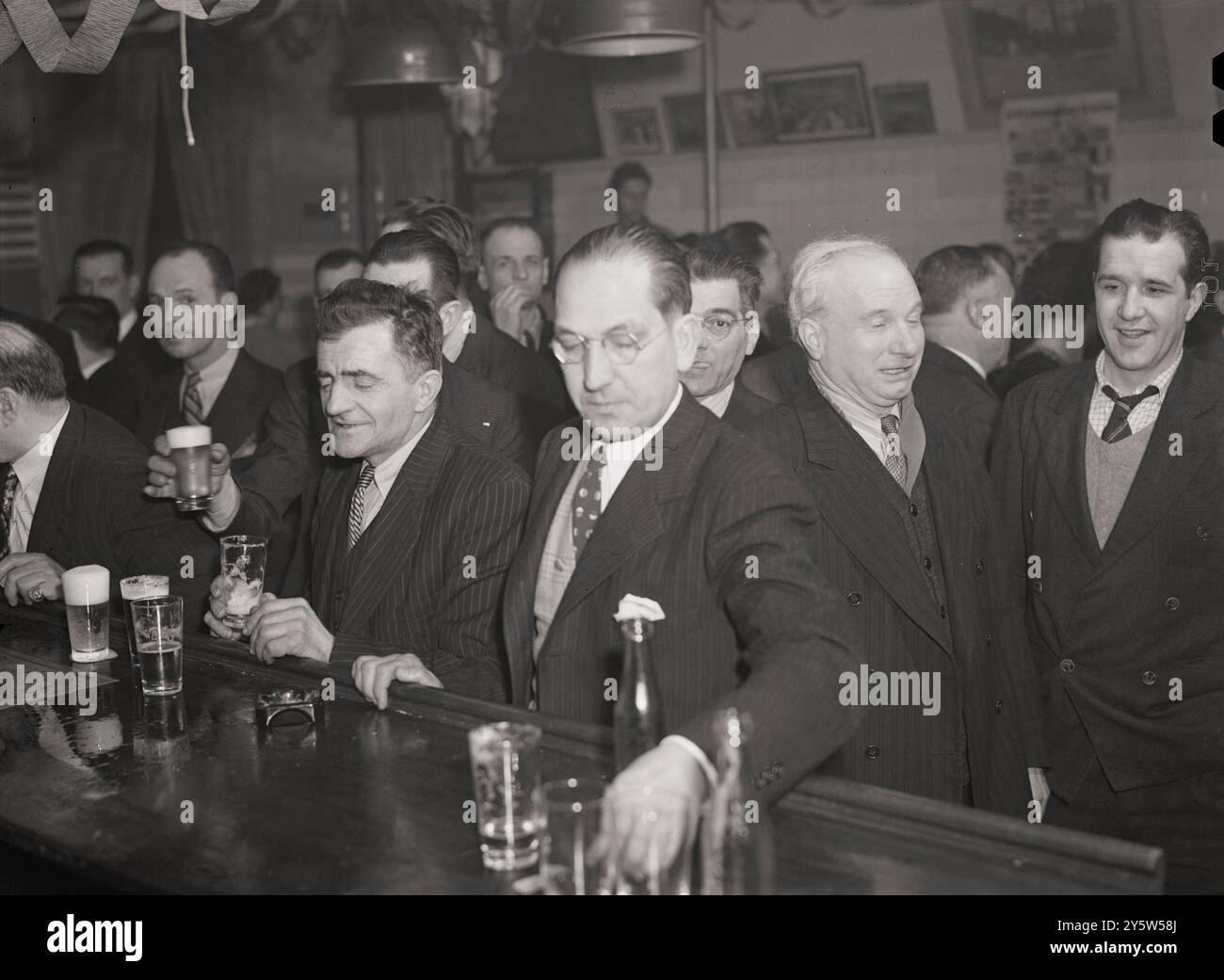 America of the 1940s. Saturday night gathering of the members of the Venetia Giulia fraternity, an International Workers' Order section made up of Italians from the southern Austria. The organization gives them sickness insurance and other benifits. Drinking beer at a bar adorned with portraits of Lincoln and Roosevelt. New York, USA. February 1943 Stock Photo