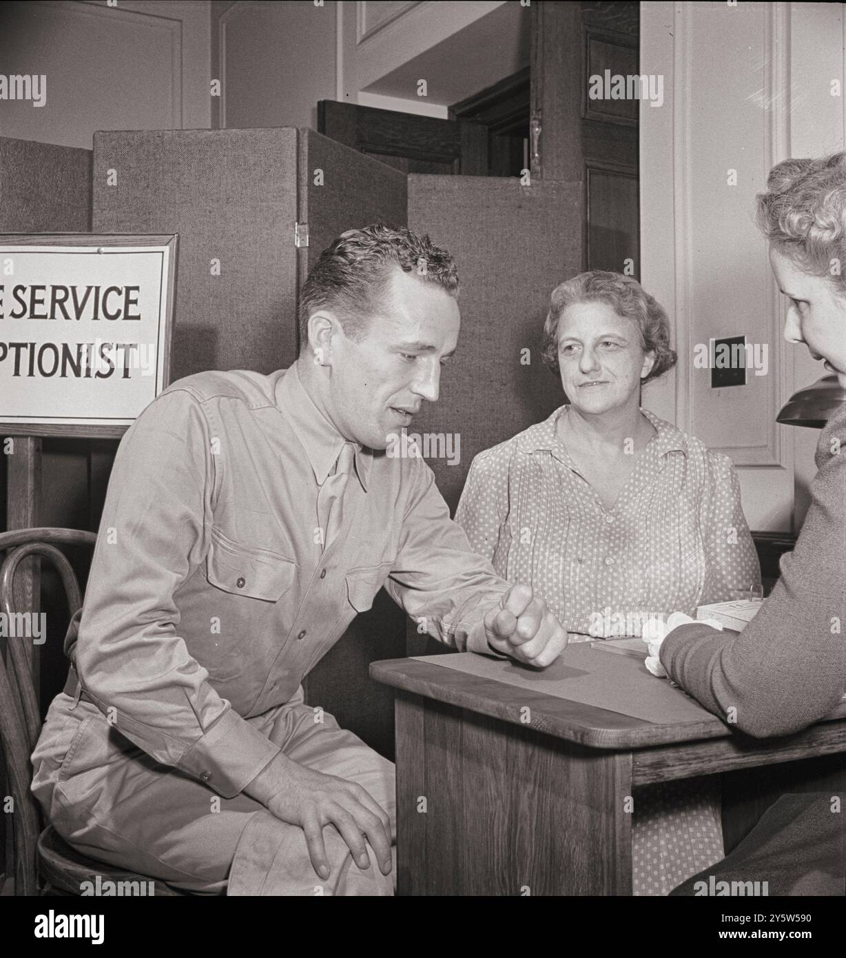 America of the 1940s. A soldier asking for help for his mother at the Red Cross home service office. This service deals with personal problems of servicemen, acts as a liaison between them and their families at home and often helps them out with loans or grants of money. USA. Washington, D.C. June 1942 Stock Photo