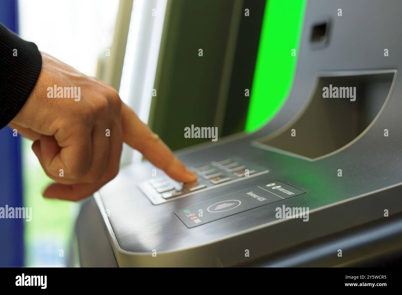A man enters a secret code at an ATM Stock Photo