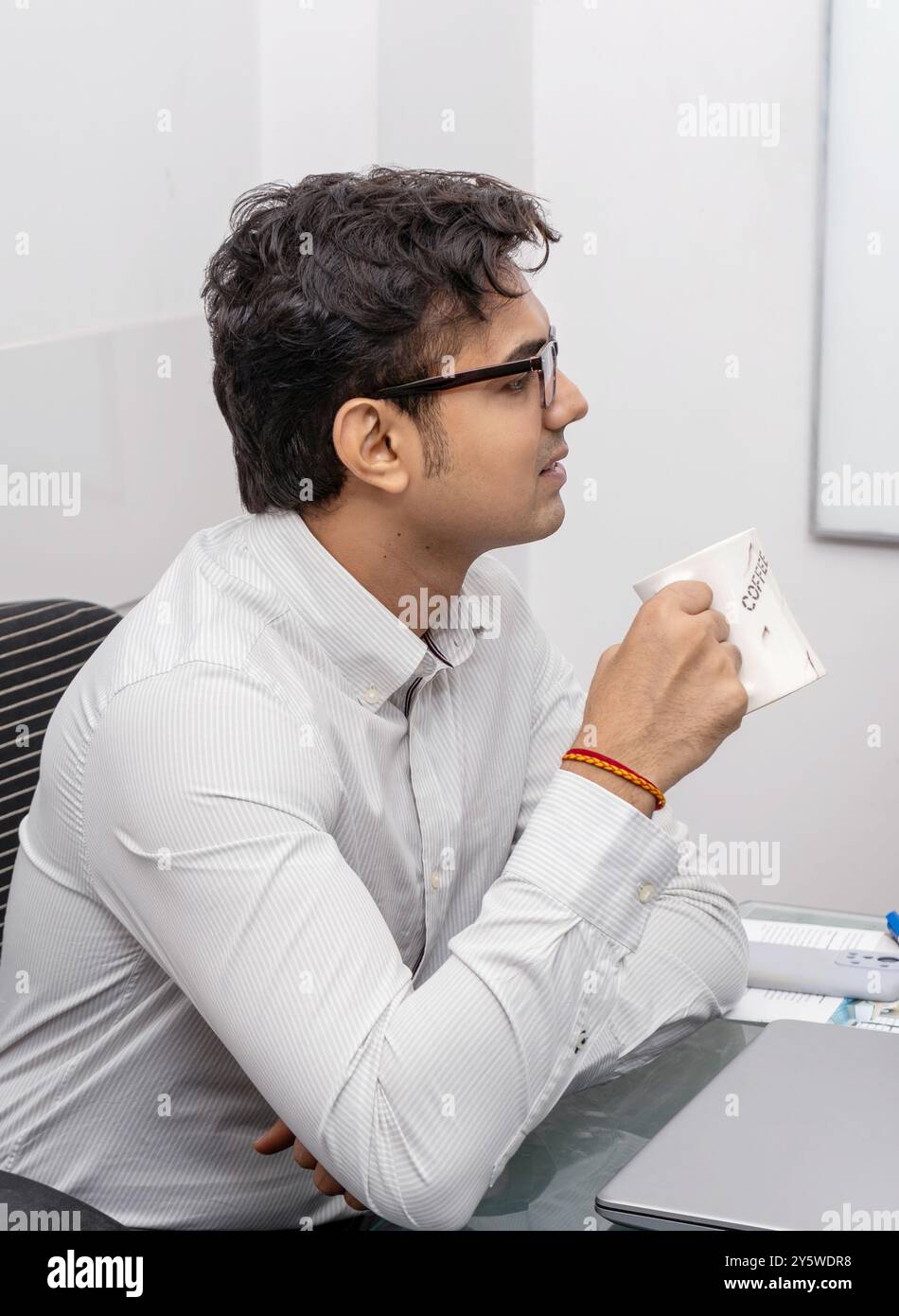 An office executive takes a moment to sip a coffee or tea as a refreshment during a meeting in a conference room where business discussions and strategy Stock Photo