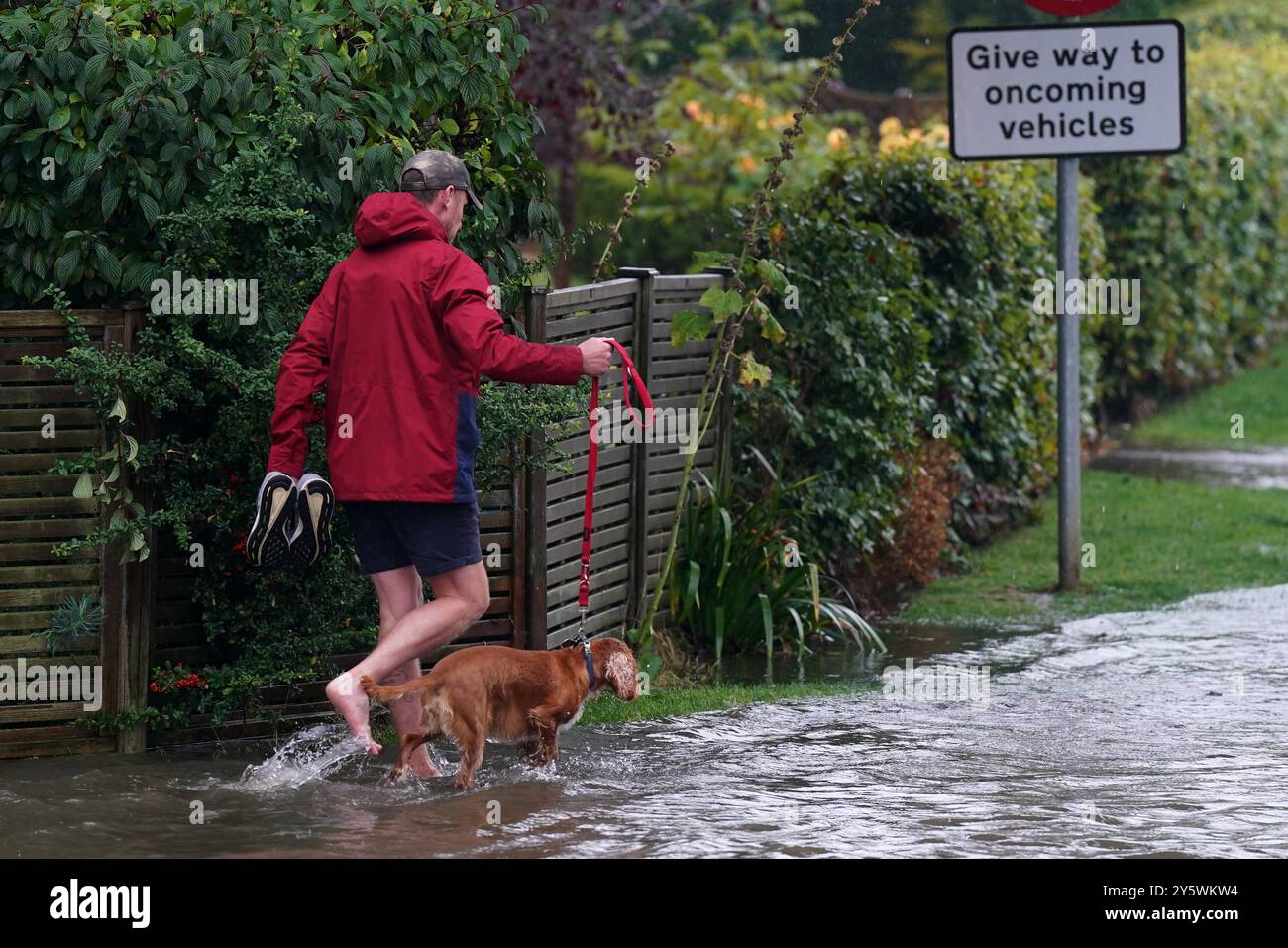 A man walks his dog on a flooded road in Willersley village, Gloucestershire. An amber weather warning for heavy rain has come into force in parts of England, with the Met Office warning that affected areas could experience more than a month's worth of rain falling on Monday. Picture date: Monday September 23, 2024. Stock Photo