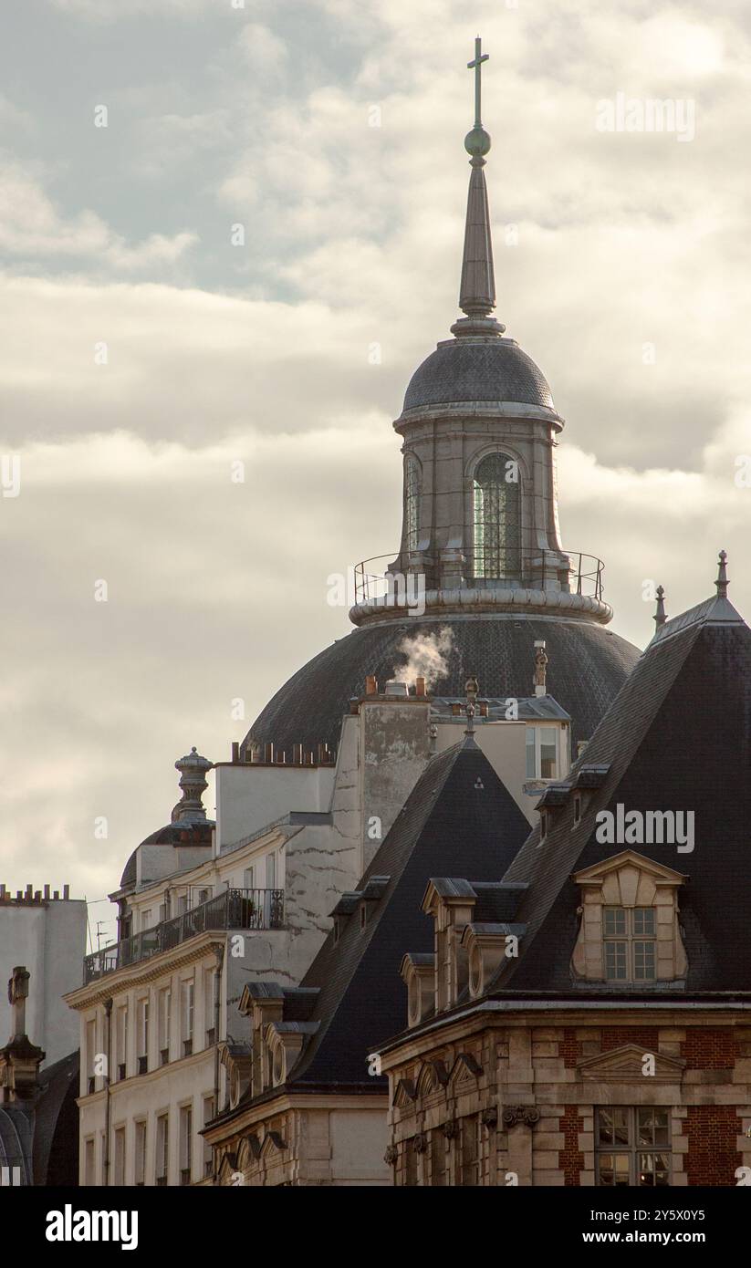 Photograph of a church in the streets of Paris under the morning sunlight agains a cloudy and warm sky Stock Photo