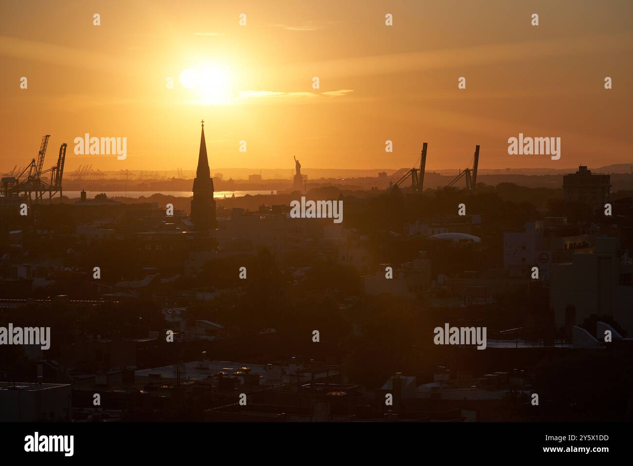 Sunset over a city skyline with silhouette of buildings and cranes ...