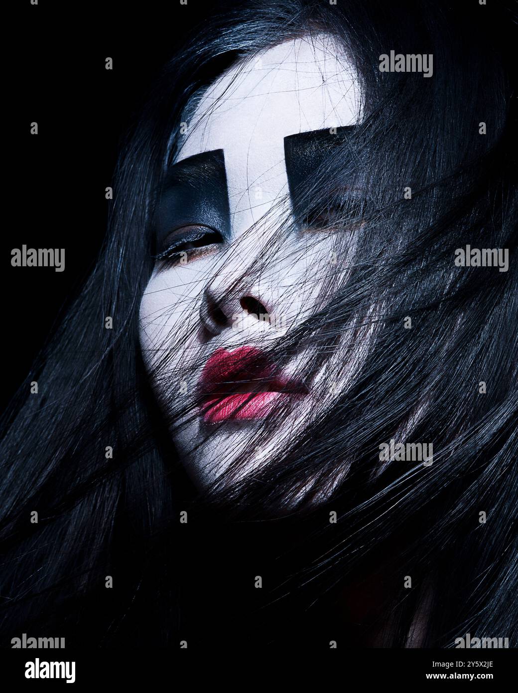 Close-up of a woman with dramatic black and white makeup and vibrant ...