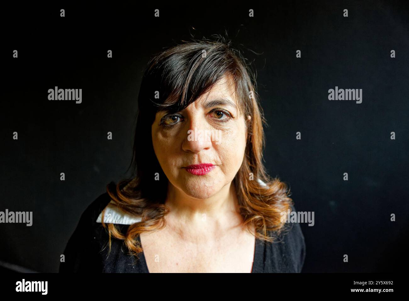 Fish-eye view of a woman with shoulder-length hair standing against a black background, looking slightly to her right with a serious expression. Stock Photo