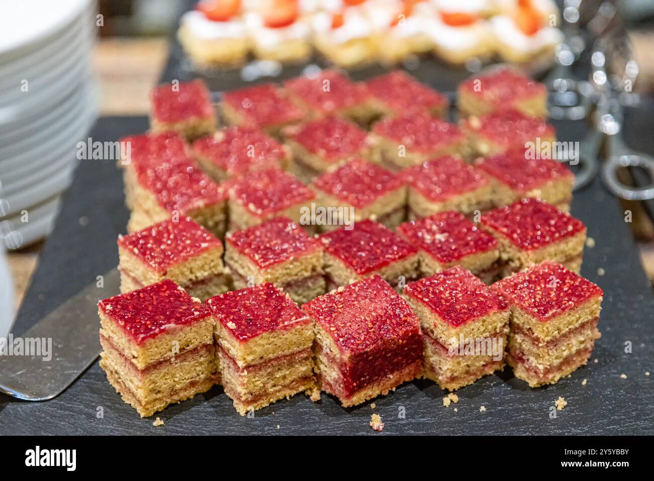 A bakery counter filled with cakes on cake stands. Lots of sweets on a table, variation of pastry products and donuts with chocolate, sugar addiction. Stock Photo