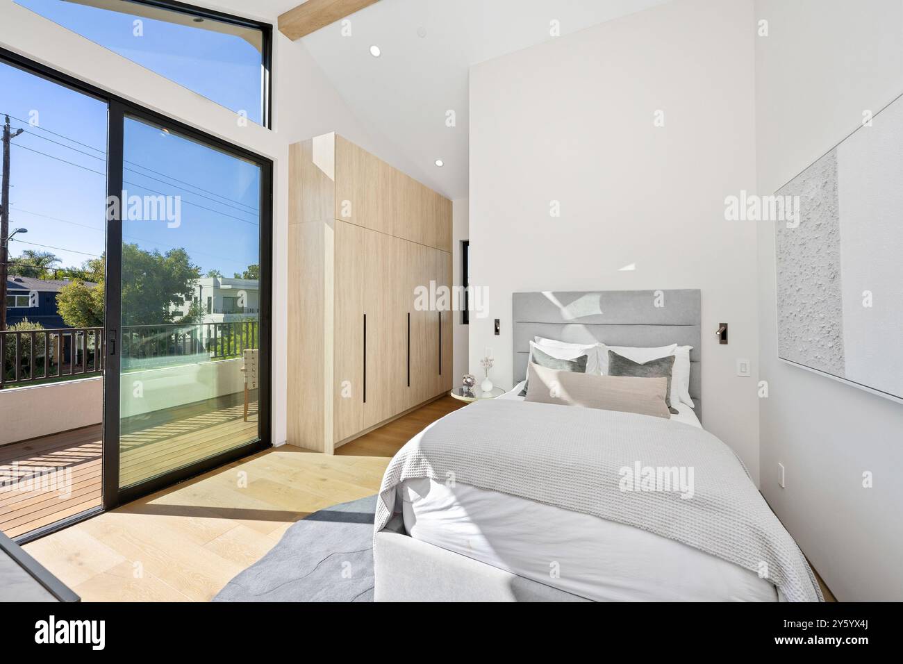Modern bedroom with large windows, wooden flooring, and minimalist ...