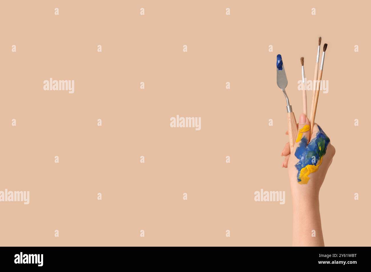 Female hand with artist's tools on beige background Stock Photo - Alamy