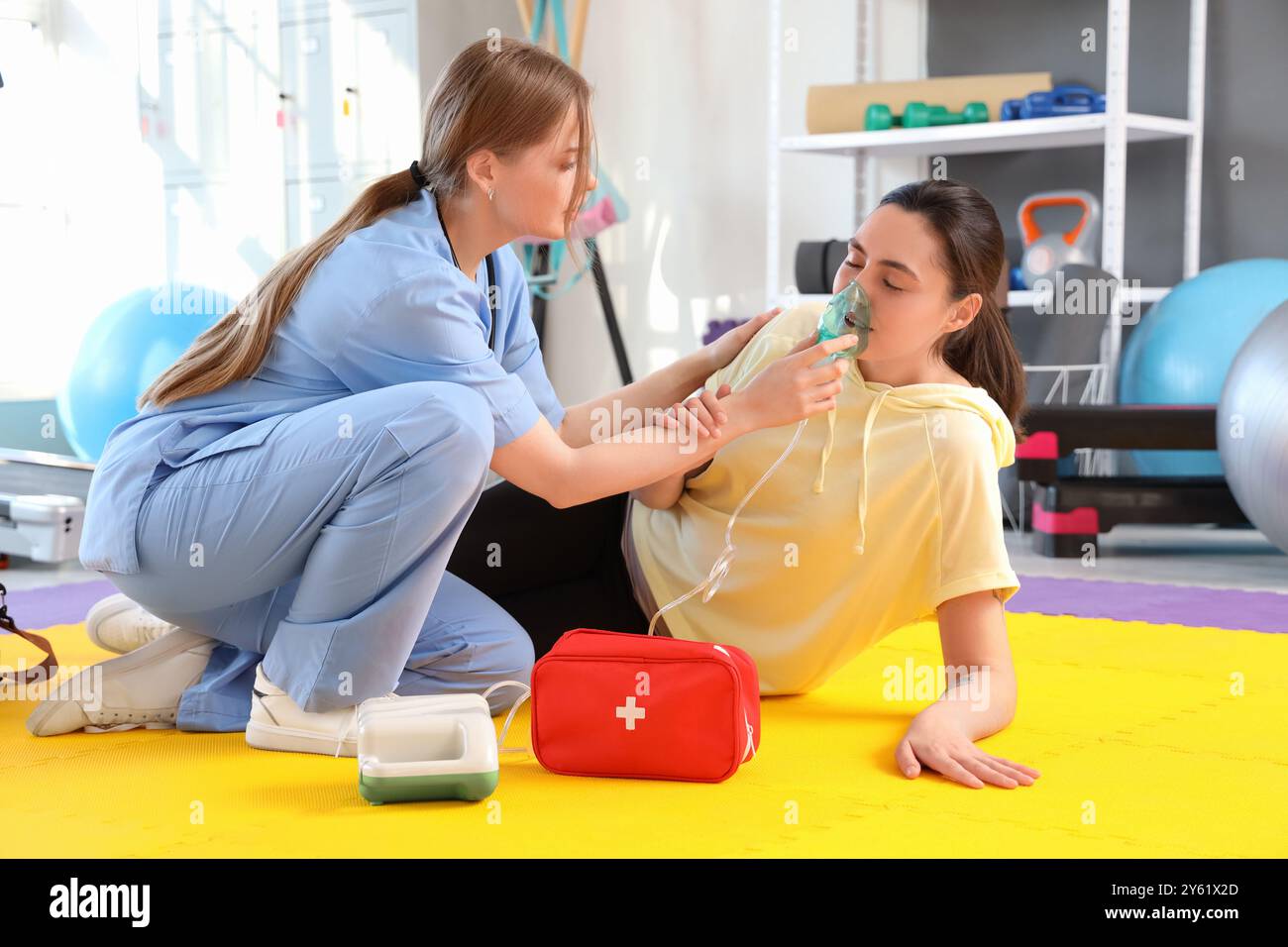 Female doctor with nebulizer giving young woman first aid in gym Stock ...