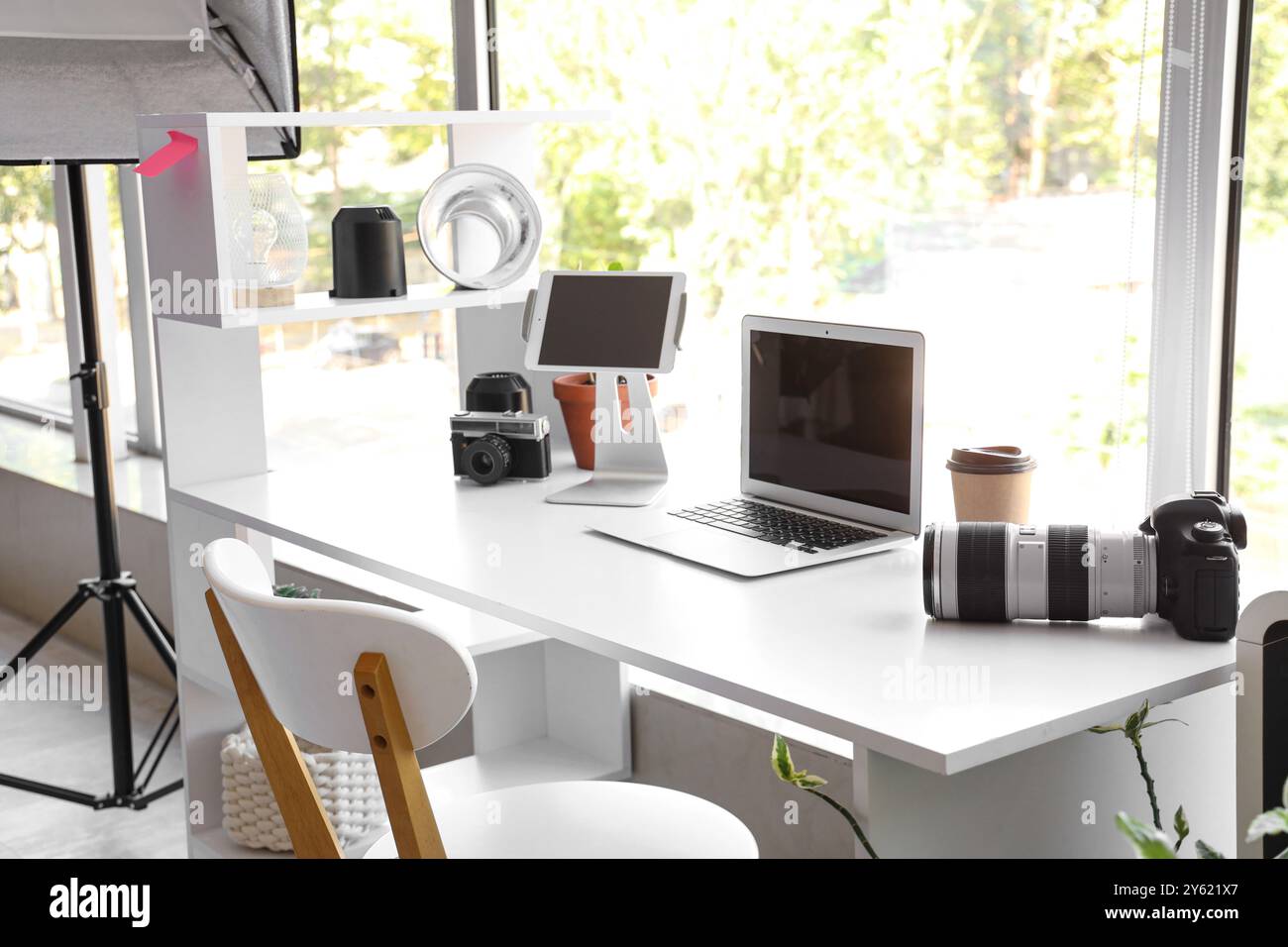 Photographer workplace with laptop, photo cameras and lighting ...