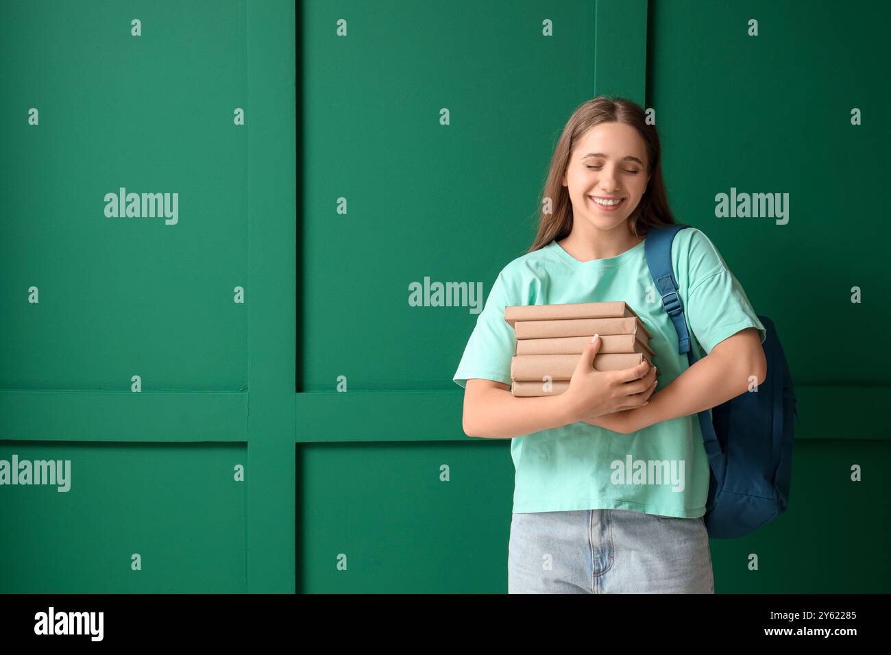 Happy female student with backpack and books on green background Stock ...