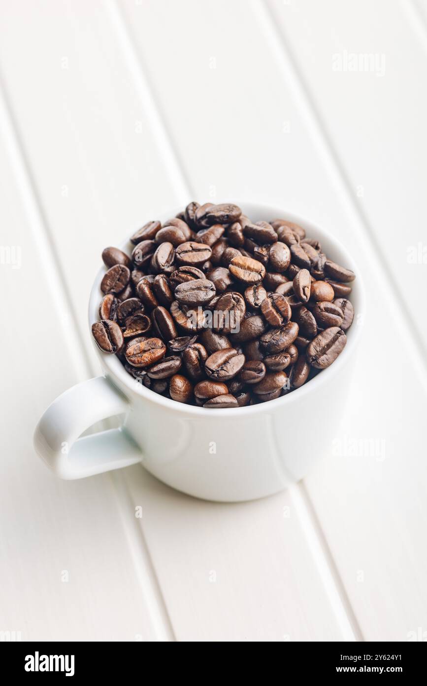 Roasted coffee beans in coffee cup on a white table. Stock Photo