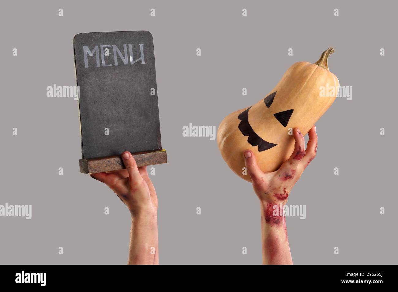 Zombie hands holding pumpkin and menu board on grey background. Halloween celebration Stock Photo