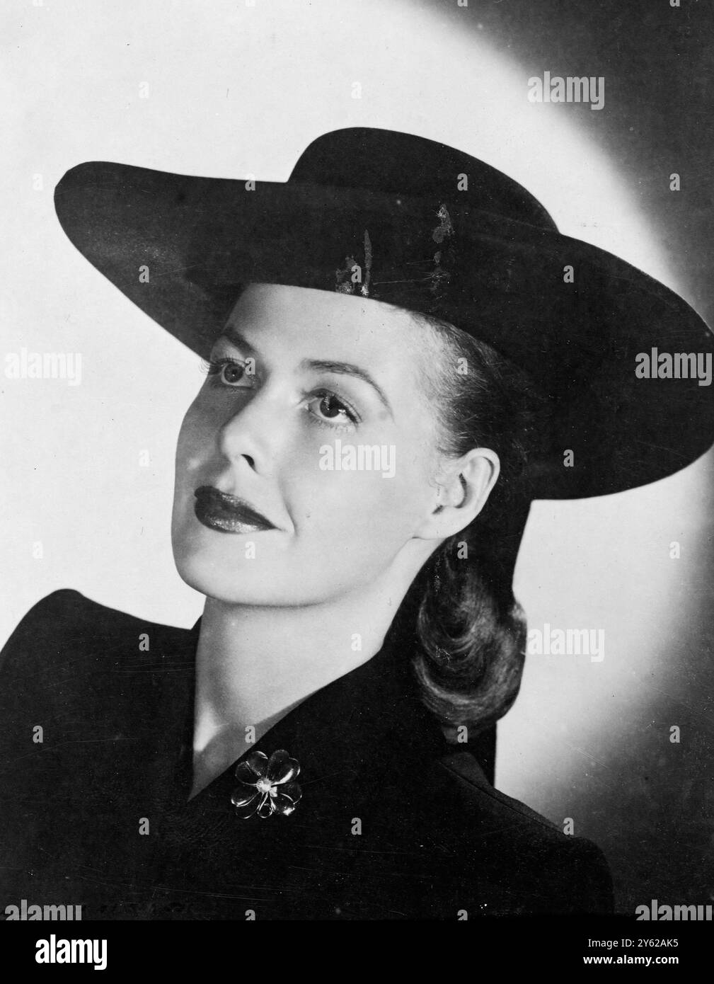 Lovely Columbia Pictures' star Janis Carter looks demurely smart in this striking black felt hat, a direct 'borrowed' from clerical costume. The black ensemble is effectively relieved, by the gold four leaved shamrock she wears on her lapel. 15 December 1947 Stock Photo