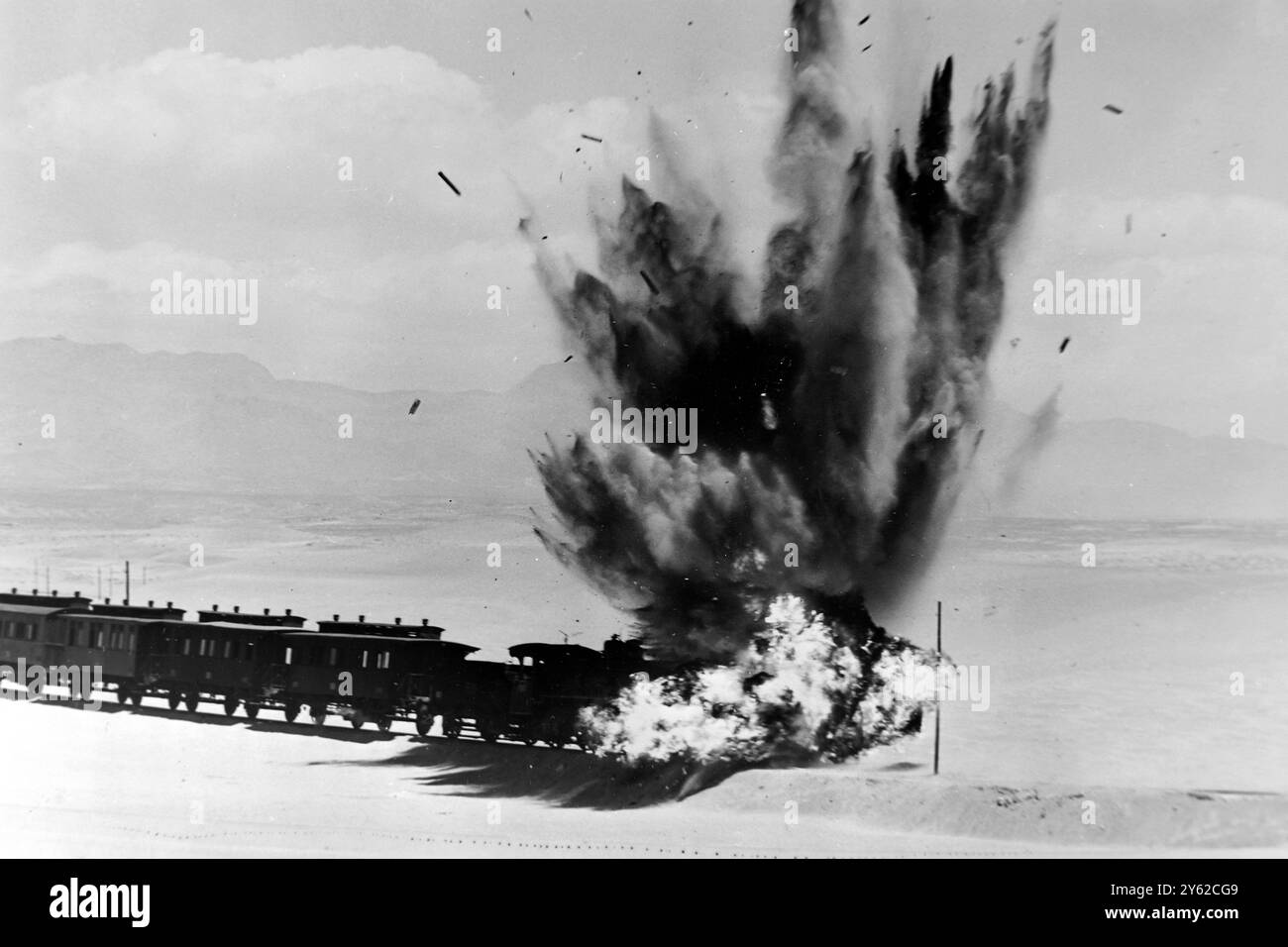 PASSENGER TRAIN BLOWN UP? Almeria, Spain : A speeding passenger train, consisting of locomotive, eight passenger cars, two freight vans and a guard's van, and with a total weight of two hundred and three tons, are blown off the track for a sequence in the film Lawrence of Arabia, now on location in Spain. Ten pounds of guncotton and ten pound of gunpowder were used to set the blast that piled up the train. Five motion picture cameras, three of them sand bagged bunkers, filmed the one shot only sequence. The train used in the shot was purchased from Spanish Railways.  18 JUNE 1962 Stock Photo