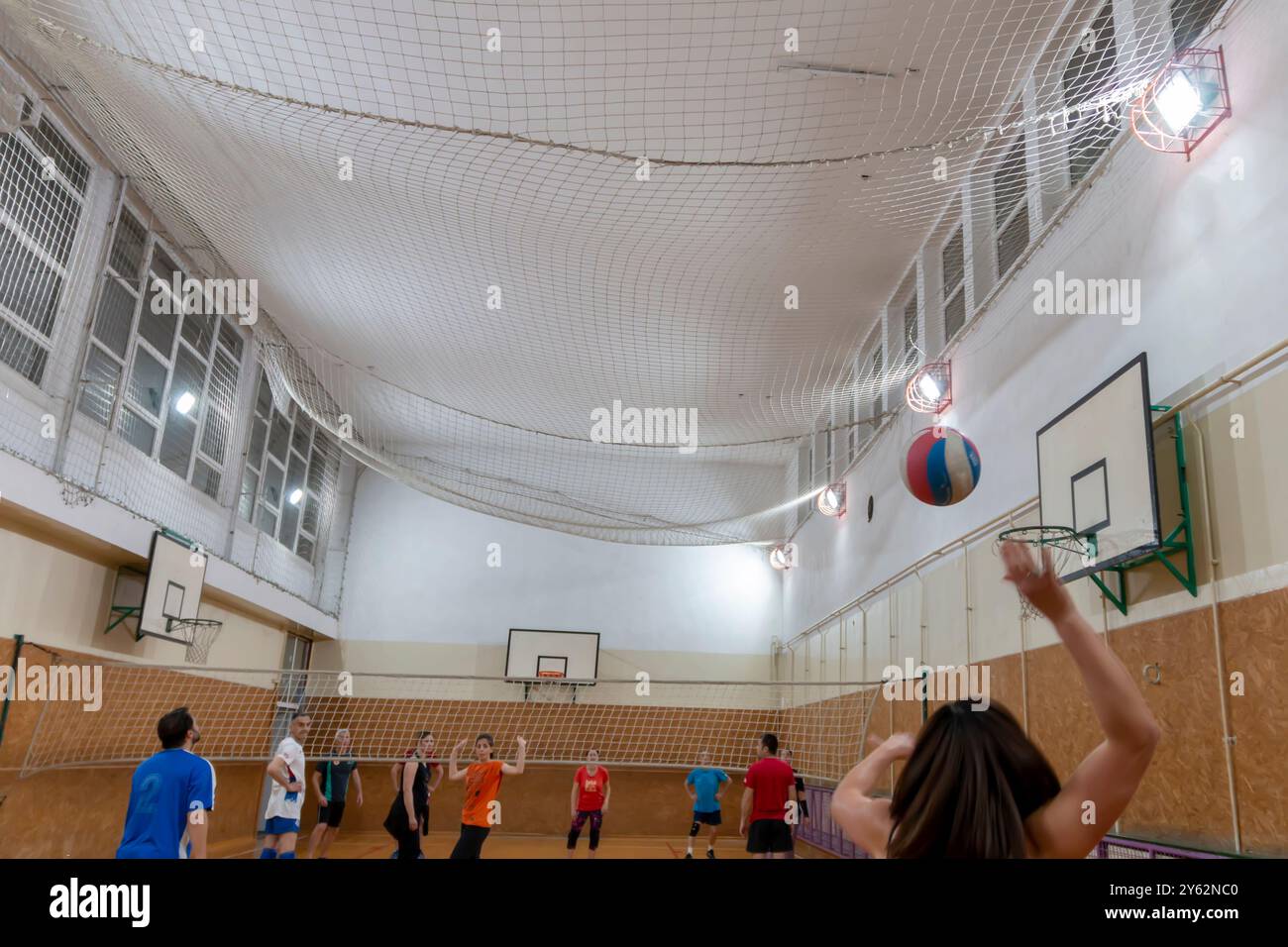 Woman serving the ball in volleyball. Friends playing volleyball. Sport  game with group of people indoor. Belgrade, Serbia - May 10. 2024. Stock Photo