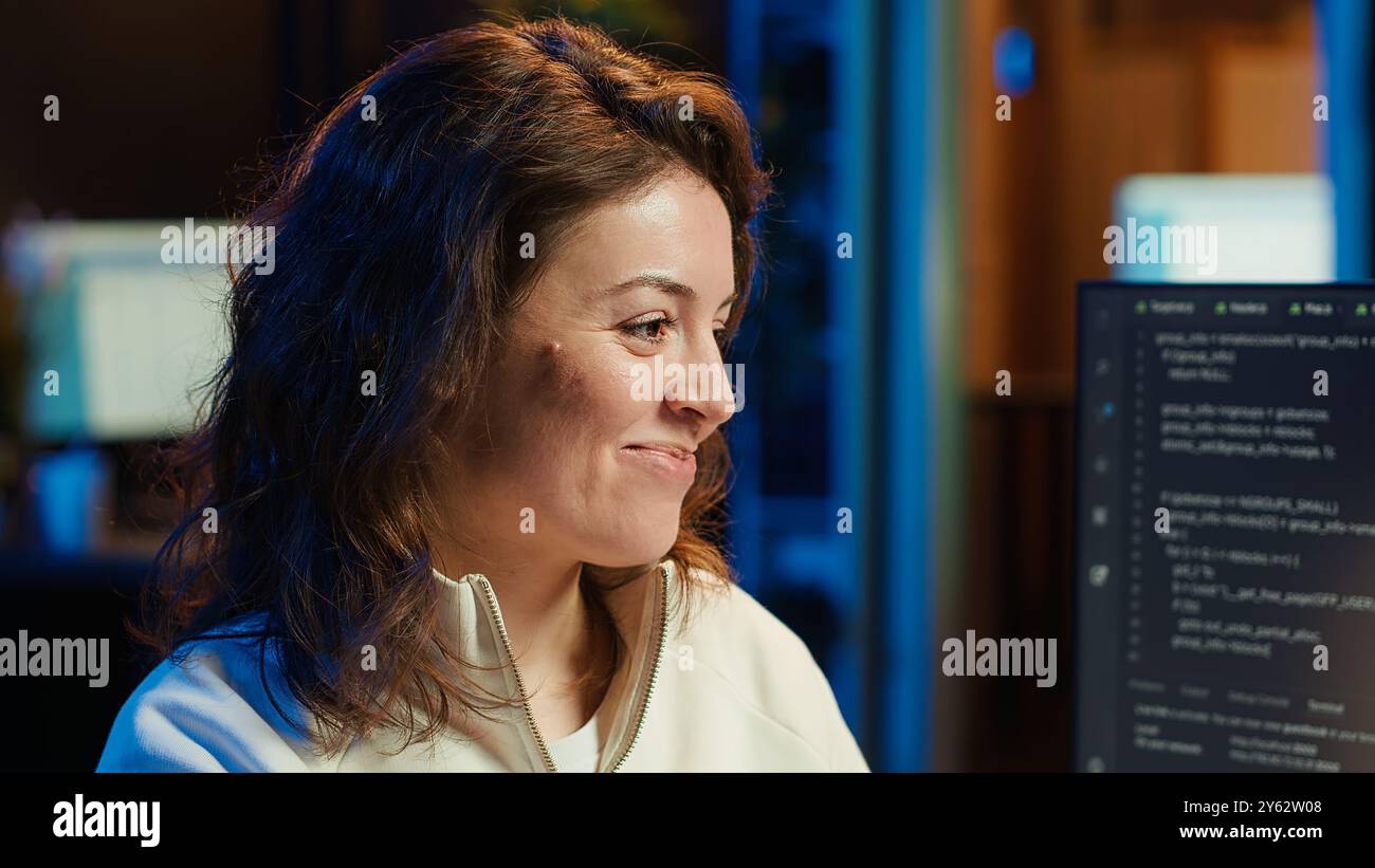 Joyous woman doing software quality assurance celebrating after reading source code and finding no errors. Cheerful engineer excited after inspecting coding on desktop PC, seeing no issues, camera A Stock Photo