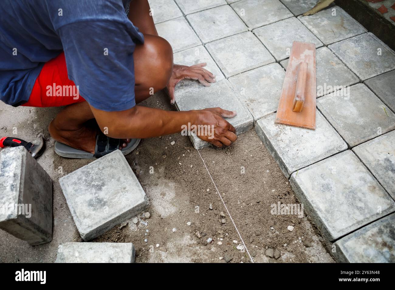 Man doing concrete block floor work for backyard patio at home Stock Photo