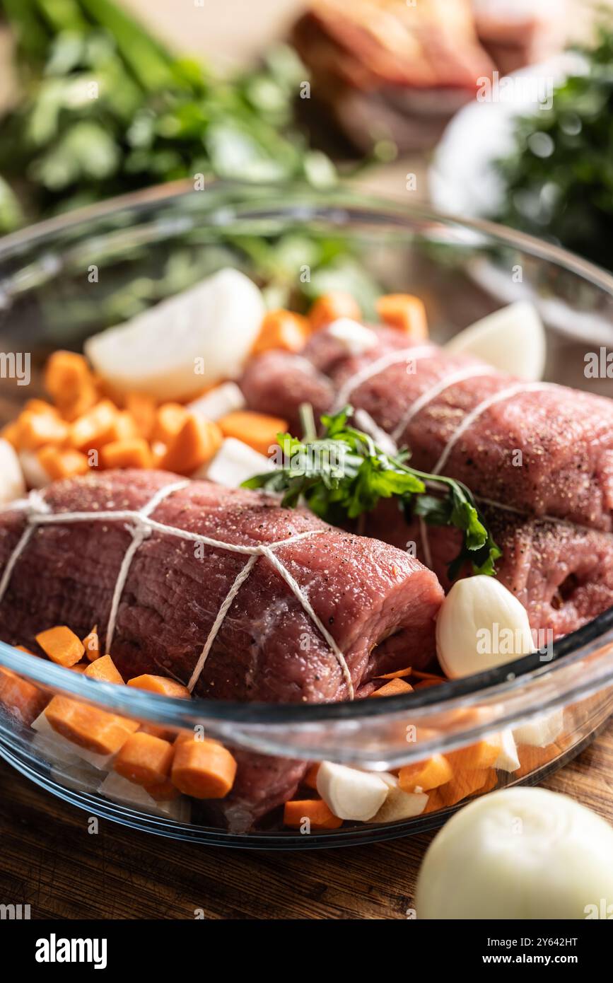 Raw beef tenderloin in a glass baking dish with root vegetables, ready to be processed into the Czech national dish - Sirloin on cream. Stock Photo