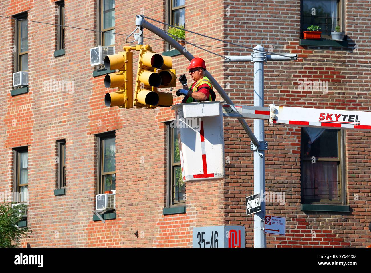An electrician in a UTEM Skytel bucket truck or aerial lift truck, wiring or repairing a traffic light or traffic signal. Stock Photo