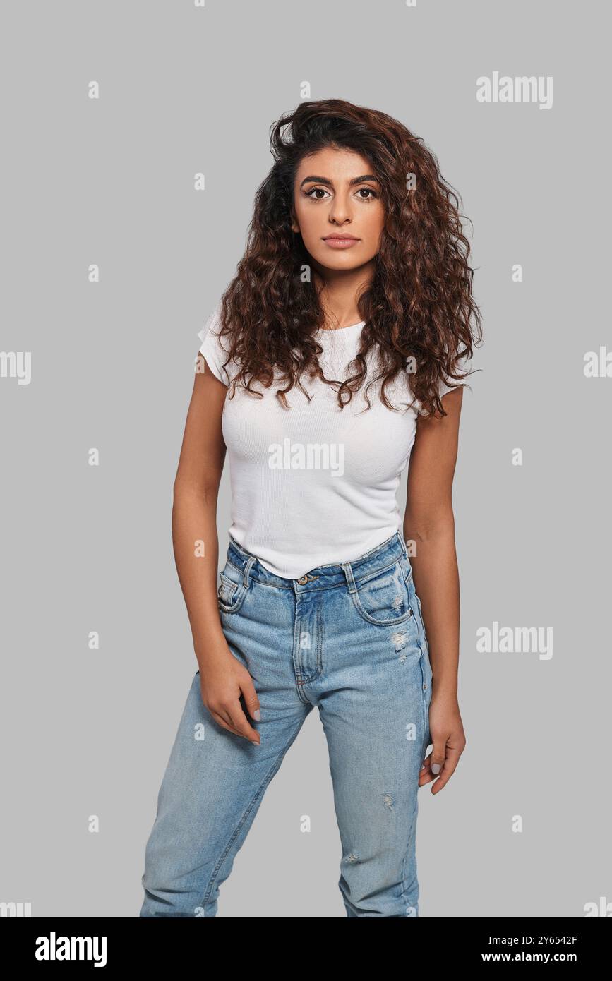 Simply stunning. Attractive young woman looking at camera while standing against grey background Stock Photo