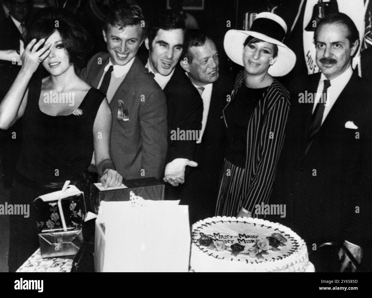 Surprise birthday party for Anthony Newley . Celebrants view a giant birthday cake at a surprise party in a New York night club last night that marked the 34th birthday of British star Anthony Newley . It also marked the 20th year in show business for Mr Newley , who is starring in The Roar of the Greasepaint and the Smell of the Crowd , a Broadway production .  Left to right are actress Joan Collins , Newley's wife ; Tommy Steele ; Newley ; Julie Stein ; Barbra Strreisand and David Merrick 25 September 1965 Stock Photo