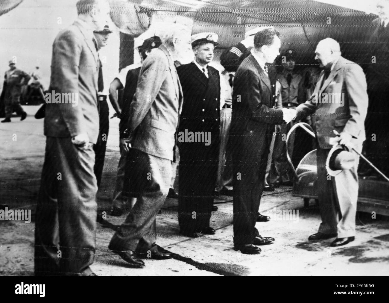 Sir Winston Churchill And Mr Anthony Eden Arrive . The scene as the British statesmen were met on arrival in  Washington by the British Ambassador , Sir Roger Makins ( extreme left ) and Mr John Foster Dulles , United States Secretary of State ( next to Sir Roger ) . In the centre , shaking hands , are America ' s Vice President Nixon ( left ) and Sir Winston Churchill ( right ) . At the extreme right , top of picture , Mr Anthony Eden can just be seen leaving the aircraft  .  25 June 1954 Stock Photo