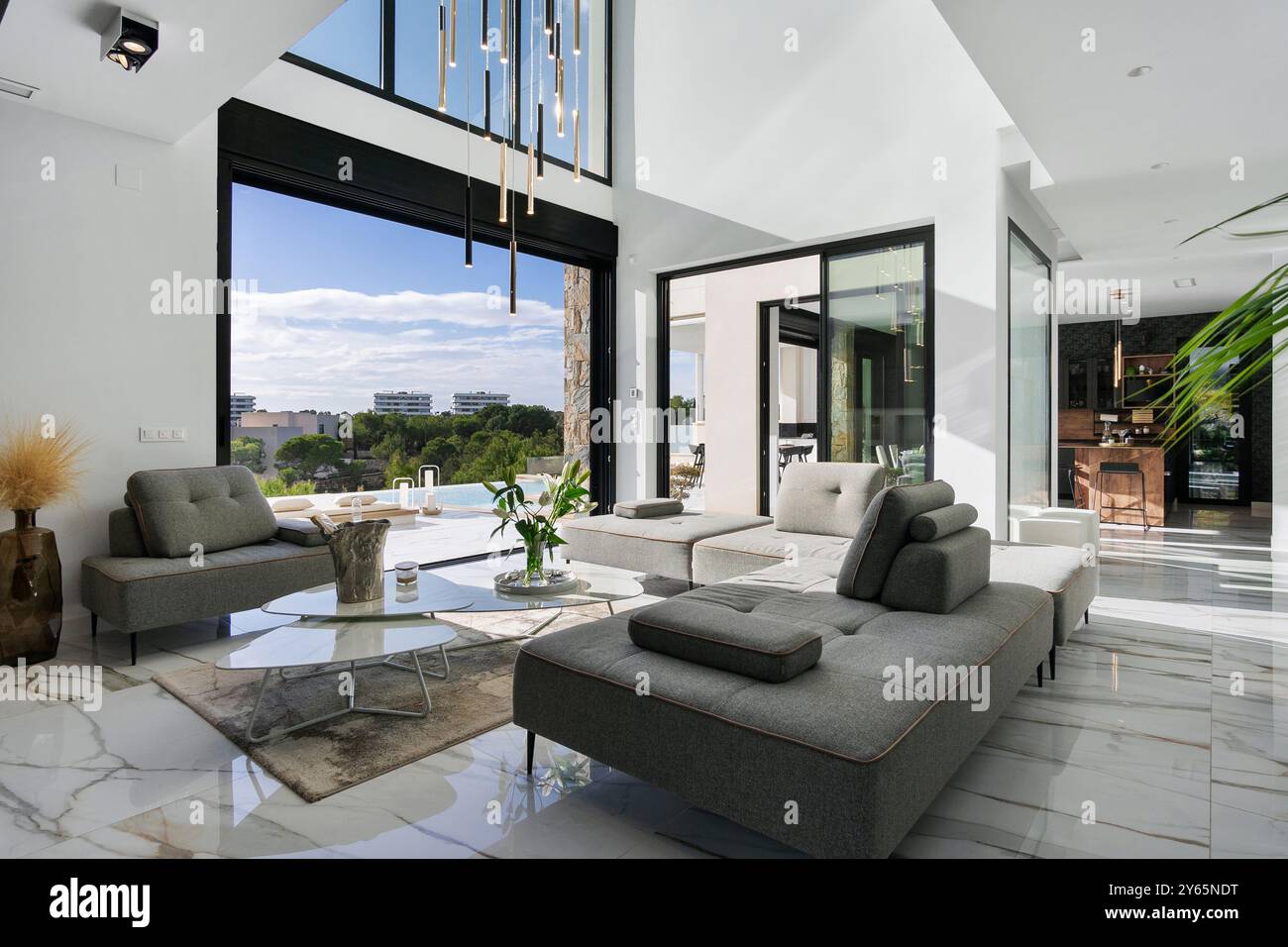 The elegantly designed modern living room opens to a serene pool, with ...