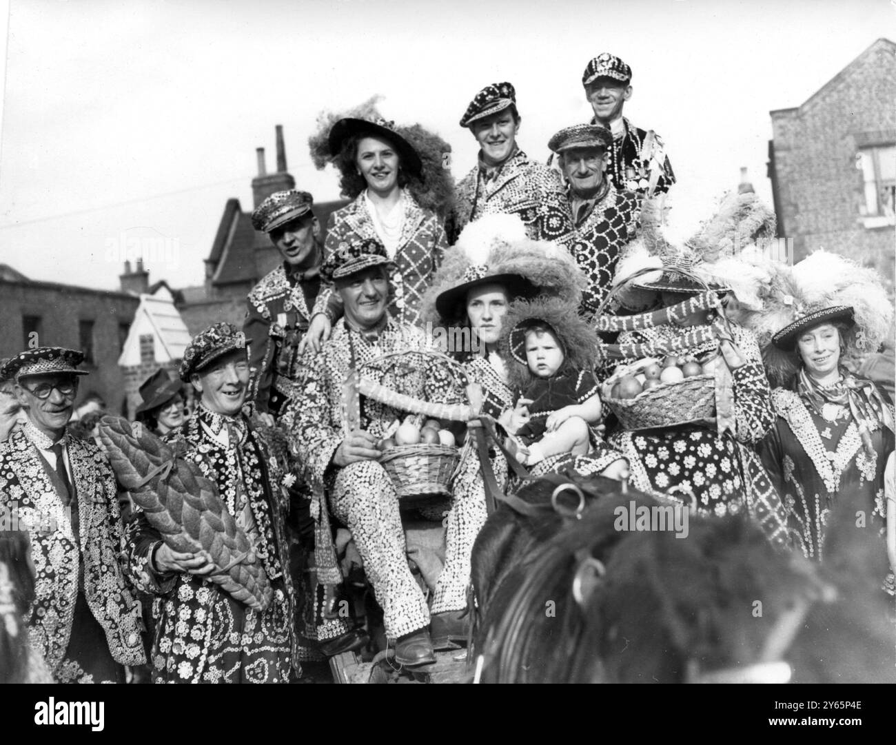 Costermongers flock to ' Pearlies ' own harvest festival . - - By donkey carts and on foot , dressed in their pearls and feathers the pearly kings and queens flocked to their own Harvest Festival service at St Mary Magdelene ' s Church off the Old Kent Road , London , bearing their offerings of fruit , vegetables and loaves . - - 11th October 1948 Stock Photo