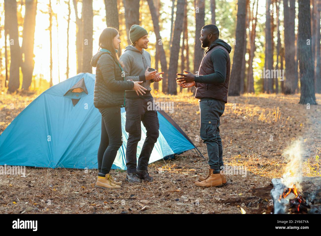 Back view of friends camping in autumn forest Stock Photo