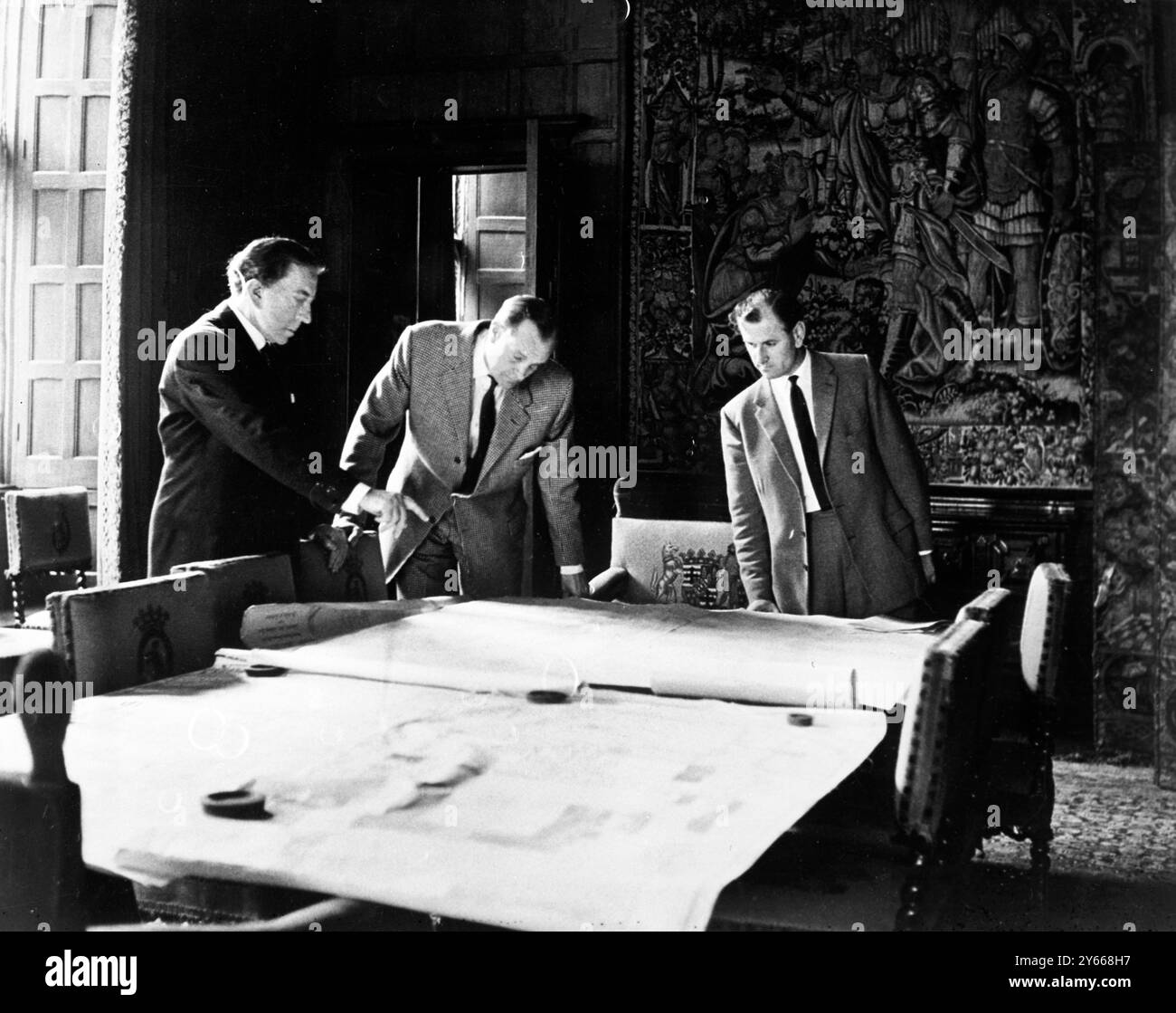 Mr Paul Getty , reputedly the richest man in the world , is seen in one of the vast rooms of Sutton Place , the Tutor Mansion near Guildford , which he is buying from the Duke of Sutherland , with Mr Dudley Delevigne (centre) who negotiated the sale for the Duke , and Mr AJ Timms , the Duke's agent (right) . Mr Getty says he is taking the house unfurnished , but will probably keep some of the furnishings and carpets . The Duke is removing most of the family pictures , including the Old Marsters , Surrey , England .16 October 1959 Stock Photo