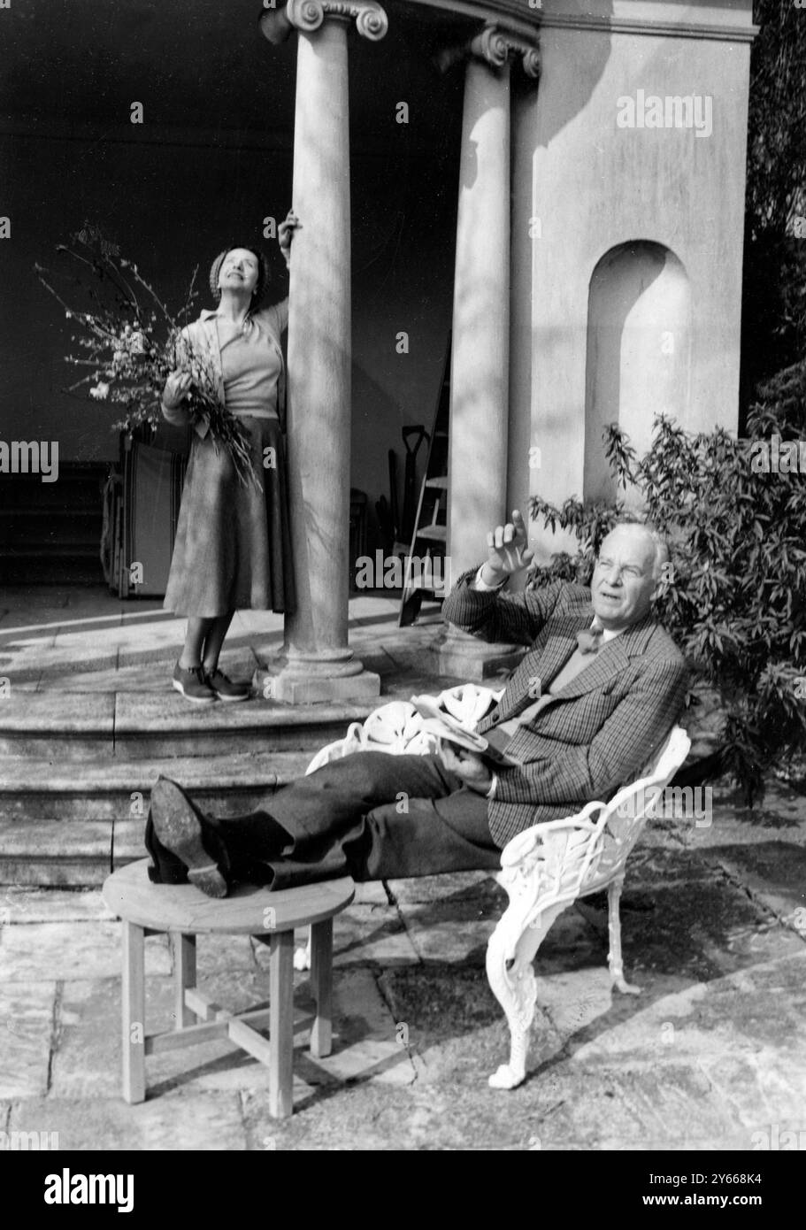 Mr Alfred Lunt and his wife , Lynn Fontanne - pictured in the lovely gardens of Lady Juliet Duff's house in Wiltshire where they stayed for a short while soon after their arrival in the country .  19 April 1952 Stock Photo