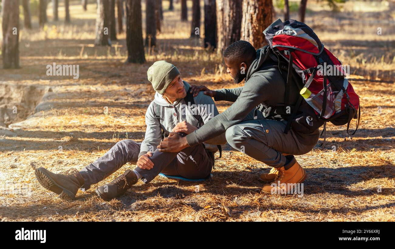Black guy helping his injured friend, hiking together Stock Photo Alamy
