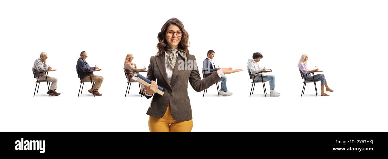 Young female teacher pointing at adult students seated in school chairs isolated on hite background Stock Photo